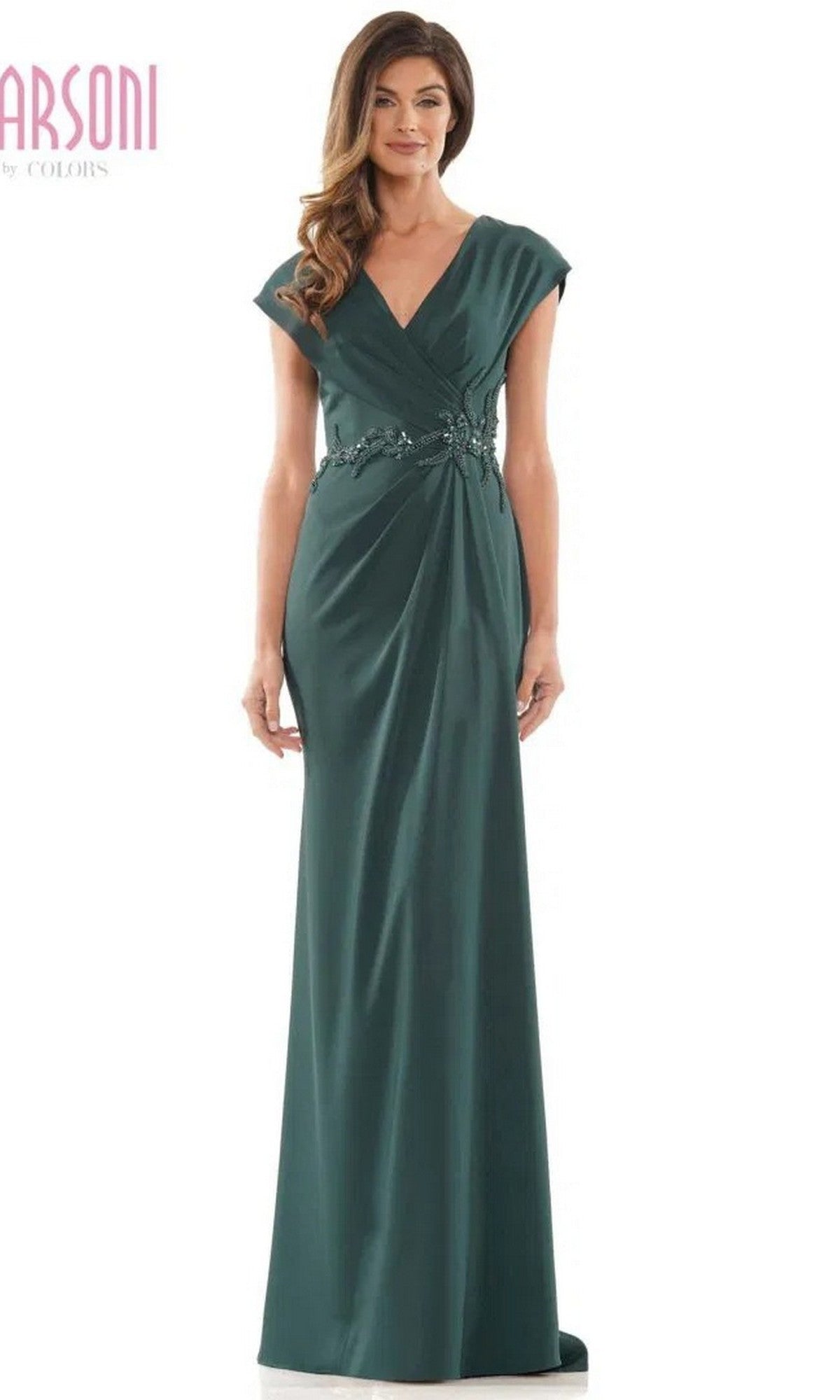 A woman wearing the Marsoni MV1226 long formal dress in deep green, featuring a floor-length sheath silhouette, cap sleeves, a V-neckline, and floral embellishments at the waist.